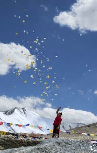 Man scattering buddhist prayer sheets at Tangangla pass on the way to Leh Kalachakra festival in july 2014